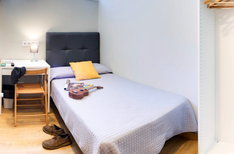 Habitación individual luminosa con escritorio y cojín amarillo